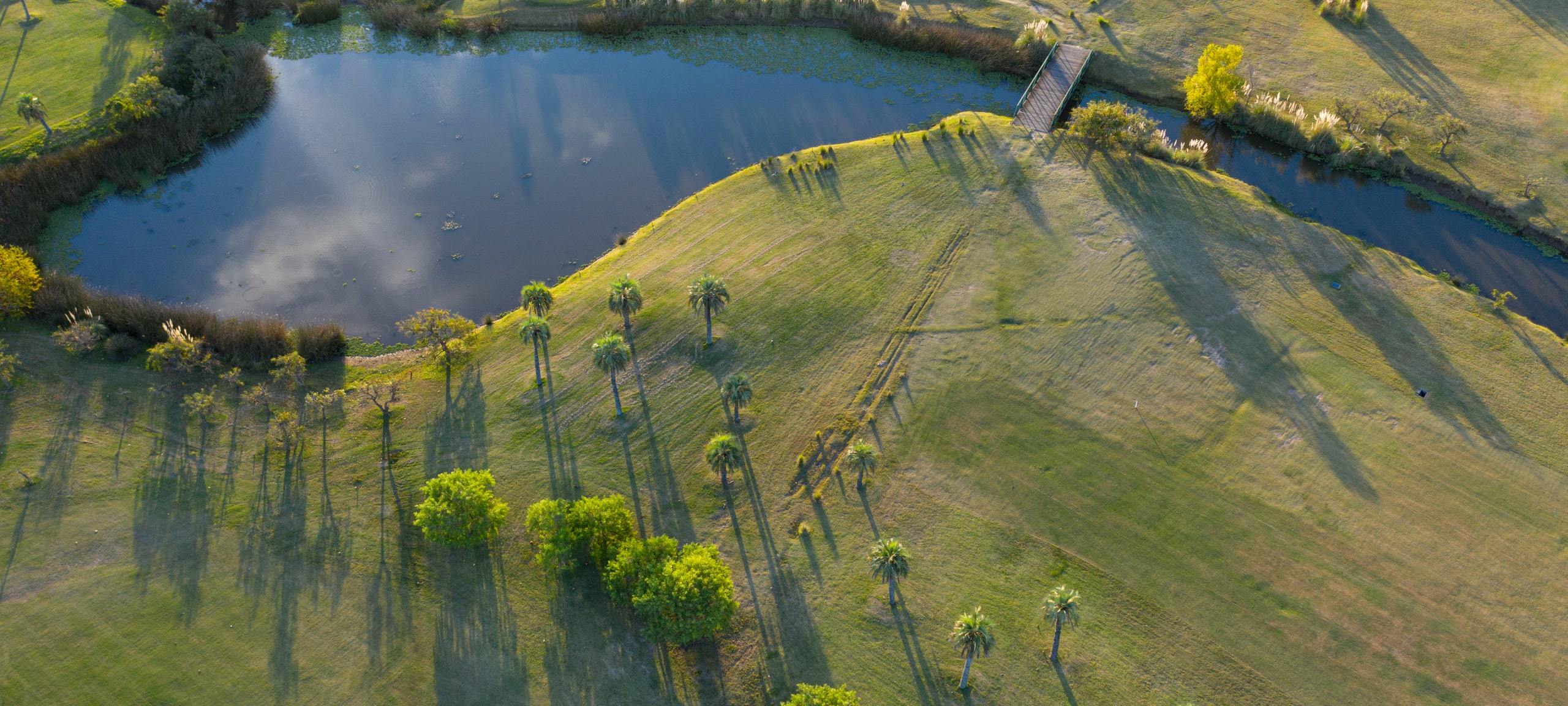 Aerial view over Austin, TX area golf course during sunset, with lake and bridge